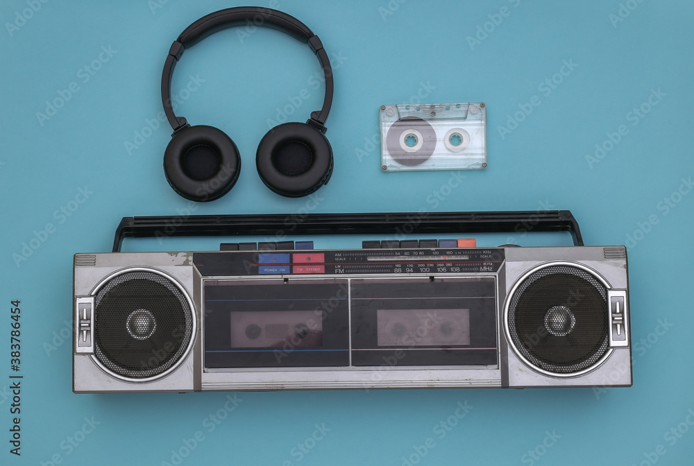 Boombox audio tape recorder, stereo headphones and audio cassette on a blue background. Retro 80s. Top view. Flat lay