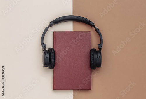 Audio book. Headphones and a book on brown beige background. Top view.