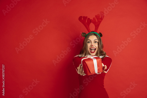 Taking gift. Greetingcard. Concept of Christmas, 2021 New Year's, winter mood, holidays. Copyspace for ad, postcard. Beautiful caucasian woman with long hair like Santa's Reindeer catching giftbox.