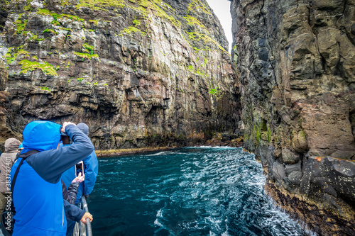 Tourists taking photos to the spectacular Vestmanna cliffs in Faroe Islands photo