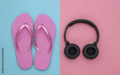 Flip flops and wireless stereo headphones on a blue-pink pastel background. Top view. Flat lay