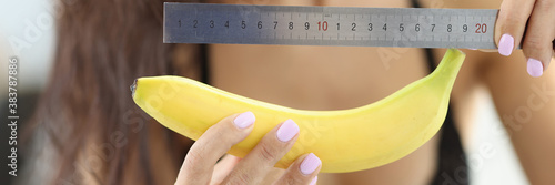 Woman in underwear holds banana and ruler. Average penis size concept photo