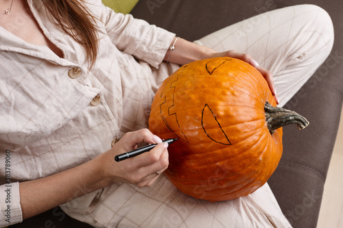 Woman painting pumpkin face and making jack lantern for Halloween