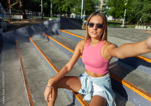 Selfie portrait of young stylish woman sitting on steps outdoors © splitov27