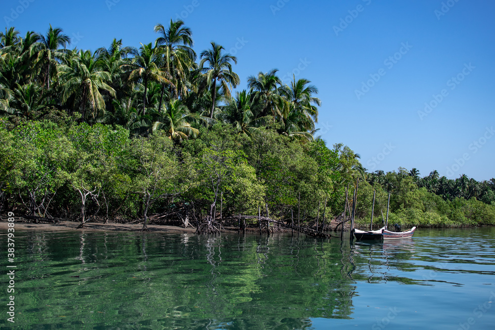 Two wooden boats in a turquoise river next to mangrove, Ngwesaung, Myanmar Two wooden boats in a turquoise river next to mangrove, Ngwesaung, Myanmar