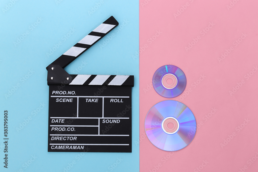 Film clapper board and cd's on pink blue background. Cinema industry, entertainment. Top view