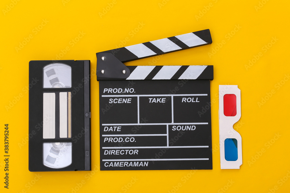 Film clapper board, 3d glasses, video cassette on yellow background. Top view