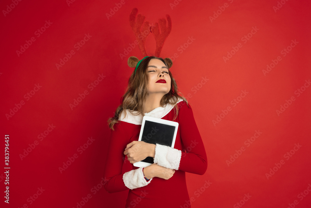 Showing blank tablet screen. Concept of Christmas, 2021 New Year's, winter mood, holidays. Copyspace for ad, postcard. Beautiful caucasian woman with long hair like Santa's Reindeer catching giftbox. Showing blank tablet screen. Concept of Christmas, 2021 New Year's, winter mood, holidays. Copyspace for ad, postcard. Beautiful caucasian woman with long hair like Santa's Reindeer catching giftbox.