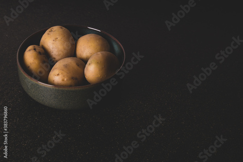 potatoes in a dark green bowl on black stone surface