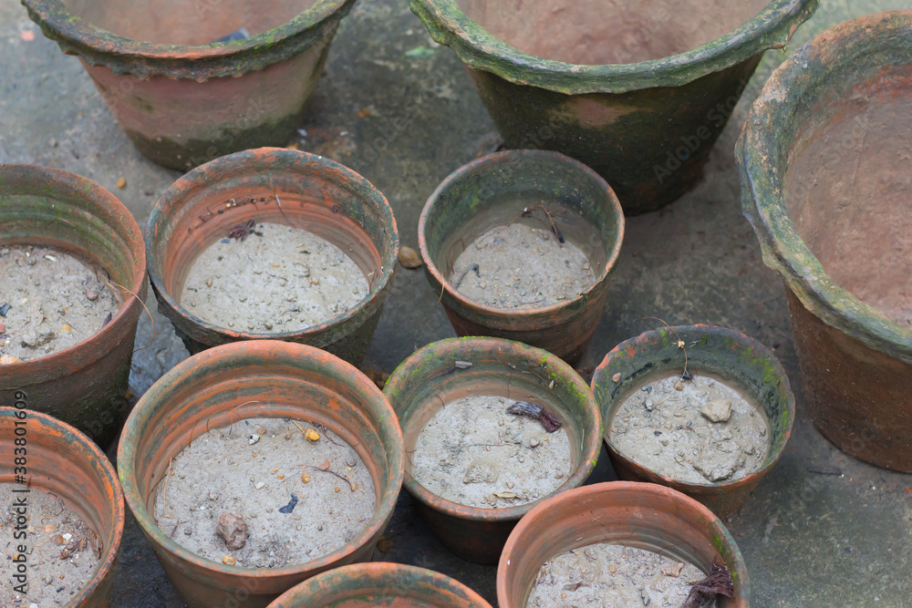 Clay pots or tubs filled with garden soil kept together for planting or gardening. Wet soil.