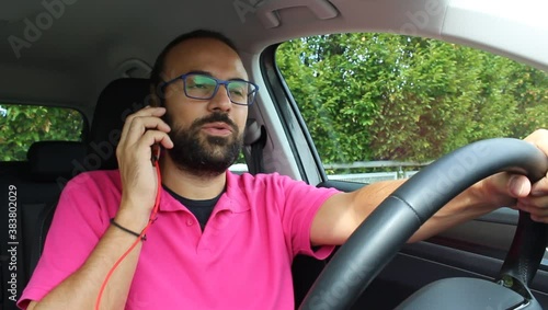 Uomo incosciente che guida la propria auto e contemporaneamente parla al cellulare - pericoloso e illegale photo