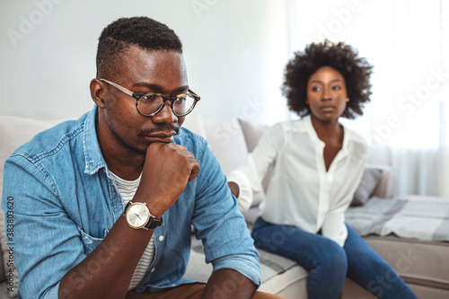 Cropped shot of an unhappy young couple after a fight at home. Unhappy young millennial married couple sitting on couch in living room after quarrel fight. 