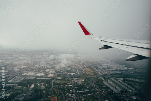 Aerial view of city landscape and airplane wing taken from the airplane window seat during take off