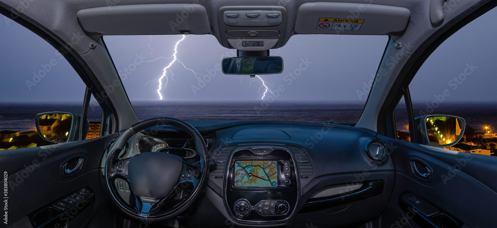 Car windshield with lightning storm over the sea