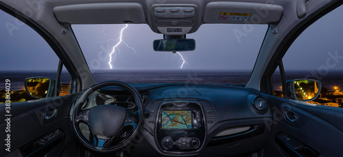 Car windshield with lightning storm over the sea