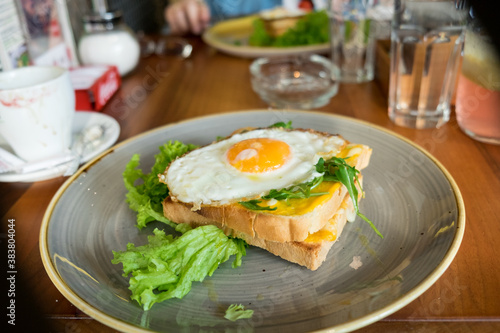 Healthy protein breakfast - crispy toasted bread with fried egg, bacon and fresh lettuce and cherry tomato