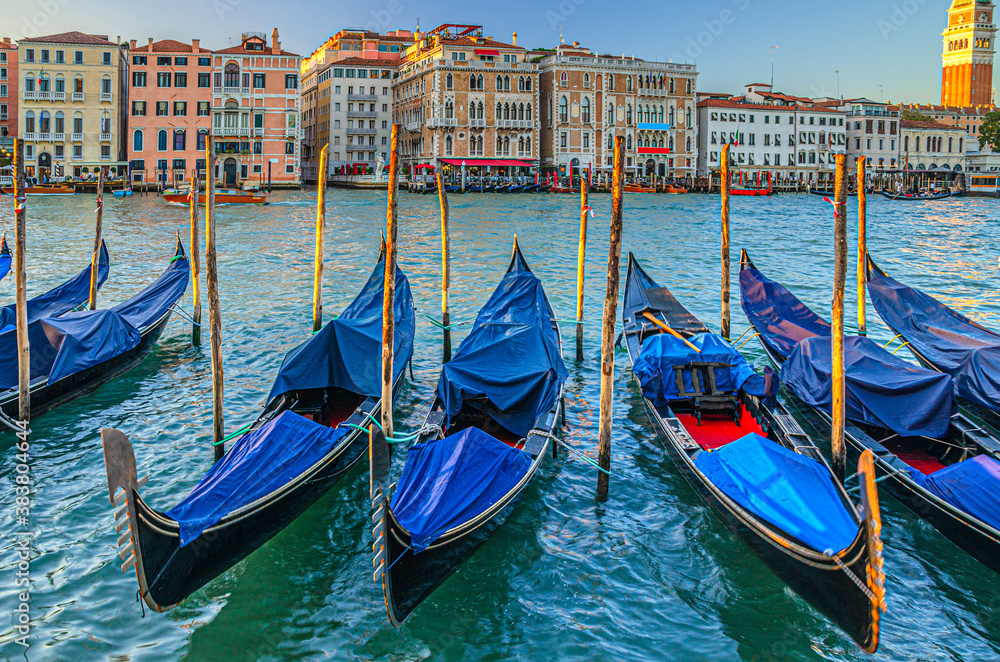 Gondolas moored in water of Grand Canal waterway in Venice. Baroque style colorful buildings along Canal Grande and bell tower Campanile di San Marco. Typical Venice cityscape, Veneto Region, Italy