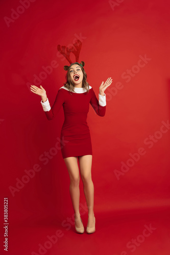 Stylish dancing. Concept of Christmas, 2021 New Year's, winter mood, holidays. Copyspace for ad, postcard. Beautiful caucasian woman with long hair like Santa's Reindeer catching giftbox.
