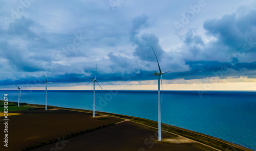 Wind turbines by the sea, generating clean energy on a stormy day. © henjon