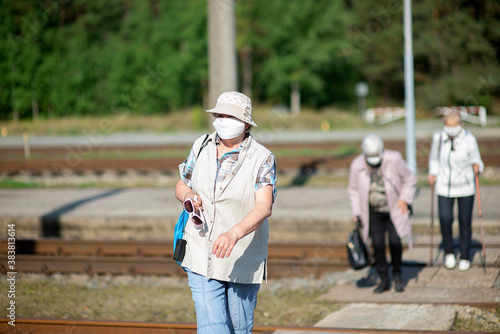 a group of senior women elderly travelers with masks on their faces cross the railway tracks