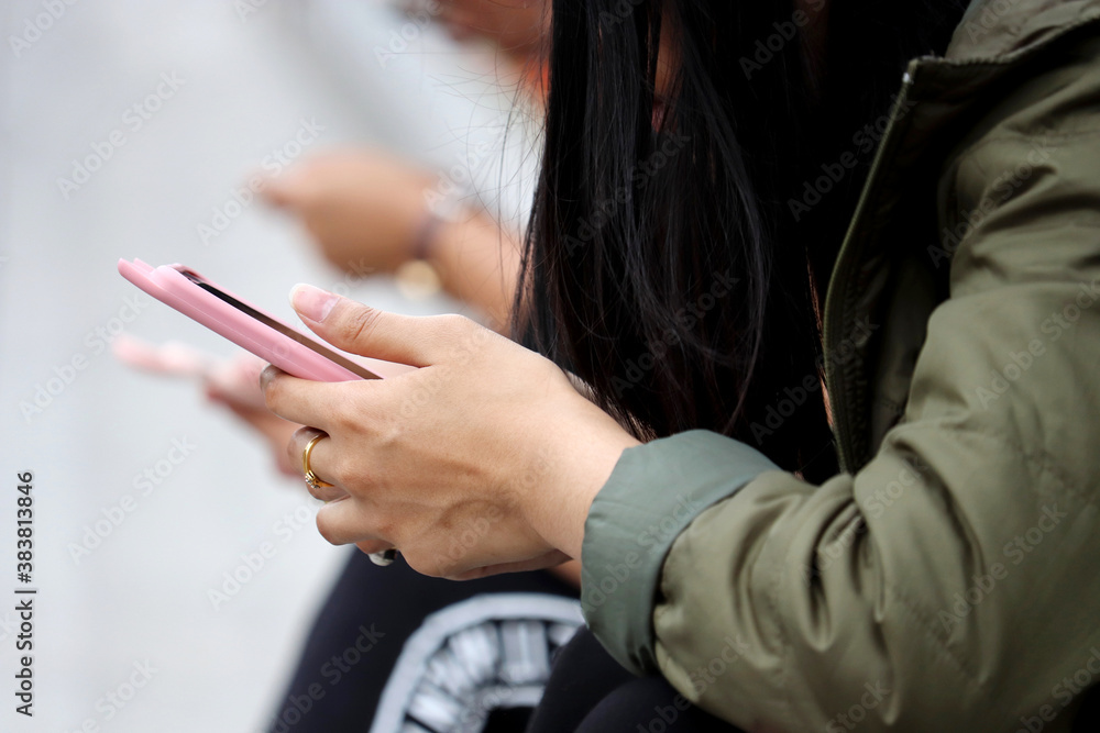 People use smartphones on a city street. Mobile phone in female hands close up, concept of online addiction, sms, social media and communication