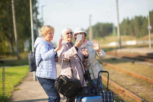 Fotografia Group of smiling senior women take a self-portrait on a platform waiting for a t