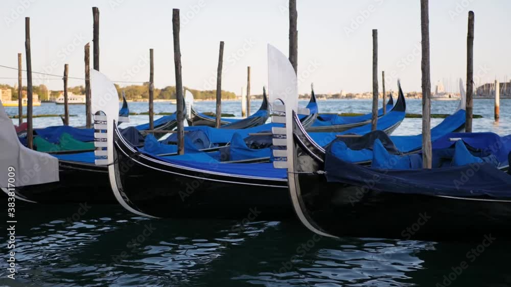 Empty covered gondola boats in Venice Italy with boats swimming on the venetian lagoon in the background Empty covered gondola boats in Venice Italy with boats swimming on the venetian lagoon in the background