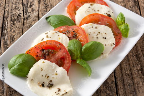 Traditional caprese salad with tomato and mozzarella cheese on rustic wooden table	