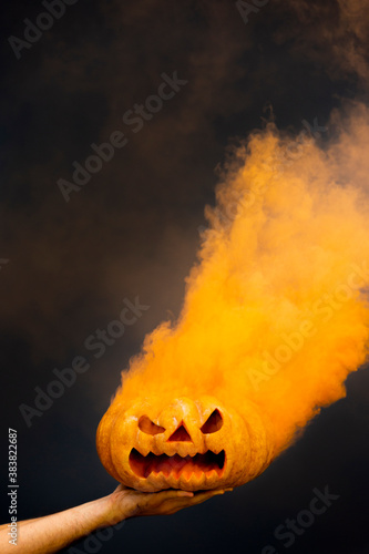 Spooky pumpkin With Orange Smoke over a black background photo