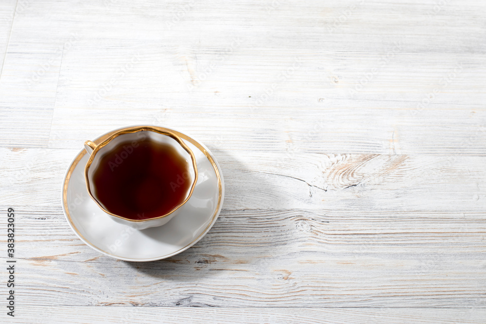 Obraz premium A porcelain cup with tea on long empty table. Space for text.