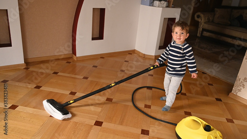 The child washes the floor with a steam cleaner photo