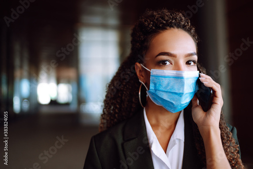 Young business woman in protective medical mask talking on phone during the Coronavirus  pandemic. COVID-19. .