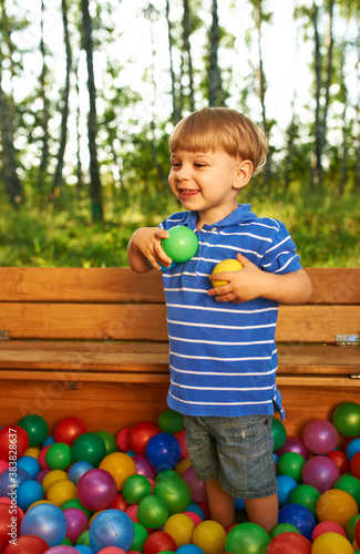 Happy child playing with colorful plastic balls photo