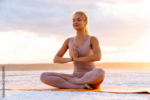 Young woman meditating with palms together and practicing yoga outdoors
