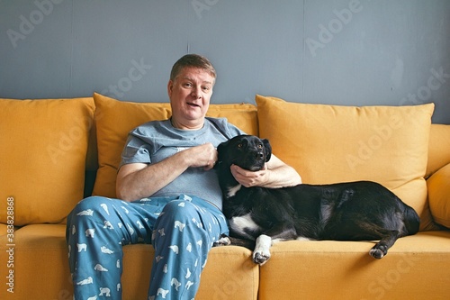 Elderly old man at home on the sofa with his pet dog © ibriholko