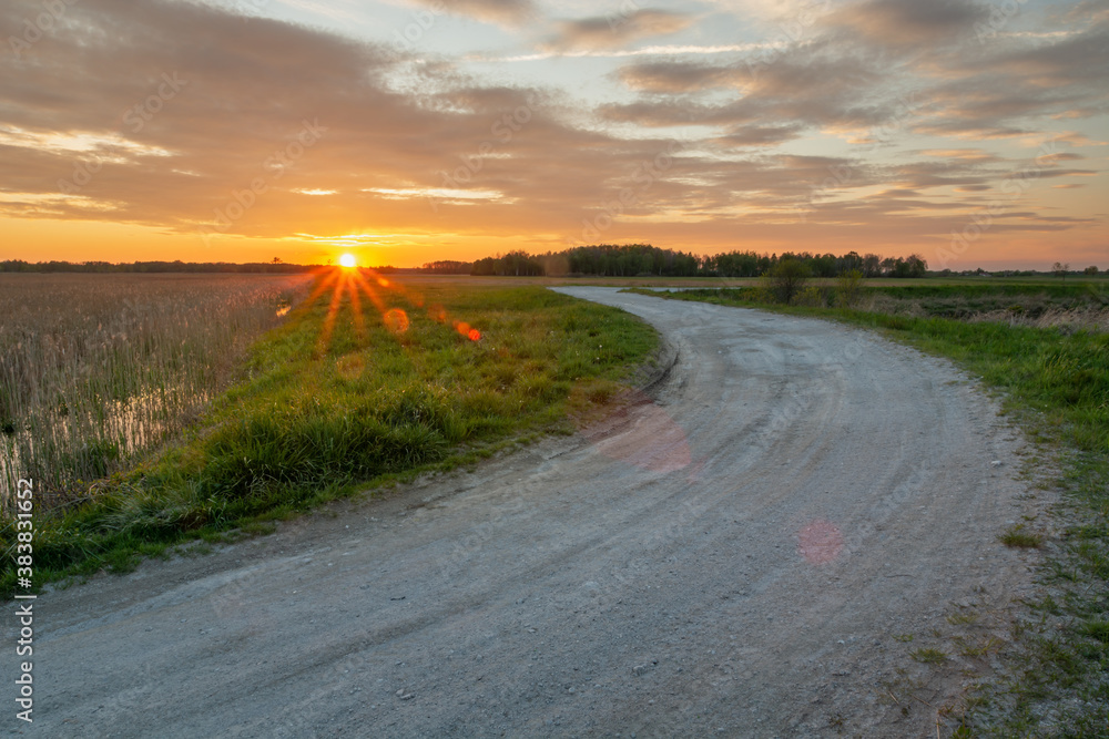 The glow of the setting sun and a turn on a gravel road