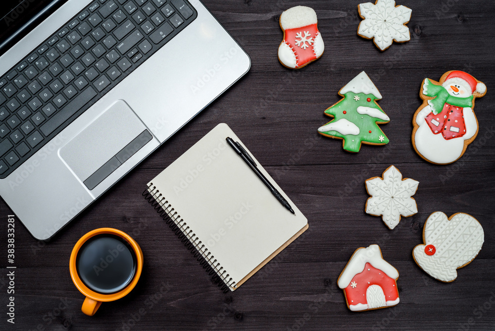 Laptop computer, blank notebook, cup of coffee and gingerbread cookies on dark wood background, copy space. Top view, flat lay. Christmas concept Laptop computer, blank notebook, cup of coffee and gingerbread cookies on dark wood background, copy space. Top view, flat lay. Christmas concept