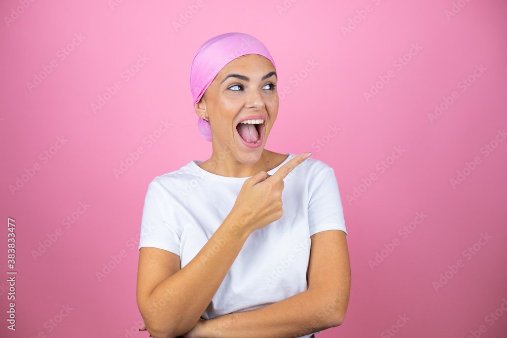 Young beautiful woman wearing pink headscarf over isolated pink background surprised and pointing with hand and finger to the side Young beautiful woman wearing pink headscarf over isolated pink background surprised and pointing with hand and finger to the side