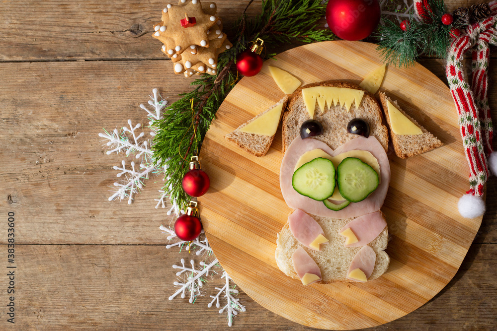 edible bull, symbol of 2021. A funny sandwich in the shape of a bull made of ham, cheese, bread, with a cucumber. children's breakfast. New Year's, Christmas food. edible bull, symbol of 2021. A funny sandwich in the shape of a bull made of ham, cheese, bread, with a cucumber. children's breakfast. New Year's, Christmas food.