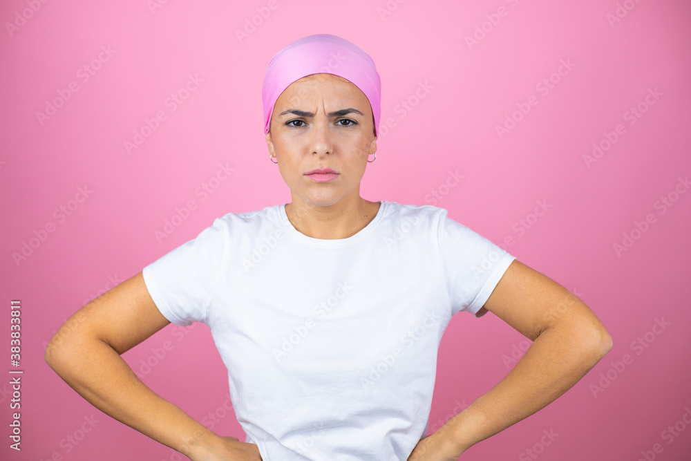 Young beautiful woman wearing pink headscarf over isolated pink background skeptic and nervous, disapproving expression on face with arms in waist Young beautiful woman wearing pink headscarf over isolated pink background skeptic and nervous, disapproving expression on face with arms in waist