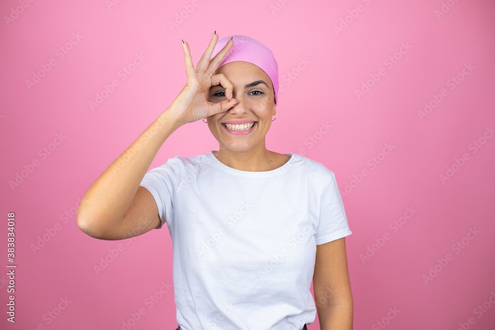 Young beautiful woman wearing pink headscarf over isolated pink background doing ok gesture shocked with smiling face, eye looking through fingers Young beautiful woman wearing pink headscarf over isolated pink background doing ok gesture shocked with smiling face, eye looking through fingers