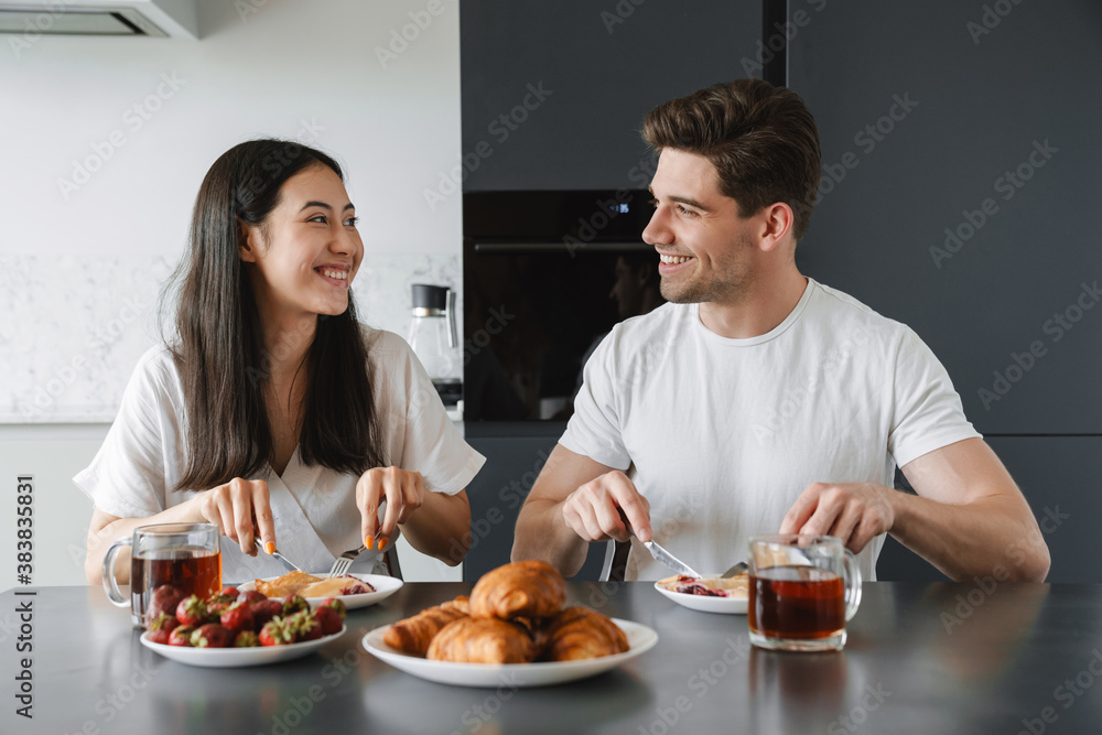 Positive young loving couple at home having a breakfast