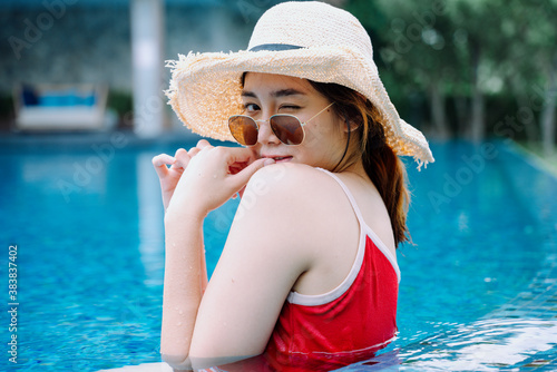 Asian woman traveler wear sunglasses and hat relax in swimming pool. © THESHOTS.CO