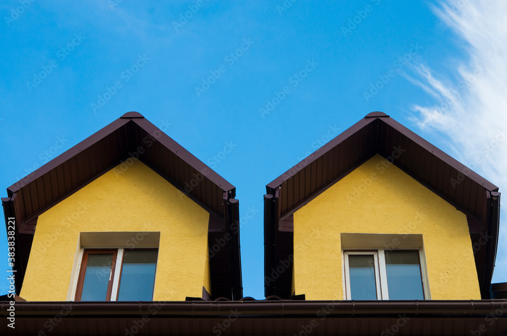 yellow houses against the sky. mansard roof with windows