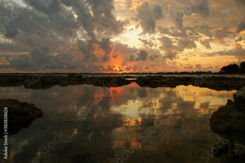Dramatic sky at sunset with red, yellow and orange colors. The reflection of dramatic clouds in the sea enhances the effect