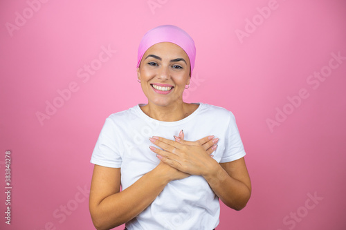 Young beautiful woman wearing pink headscarf over isolated pink background smiling with her hands on her chest and grateful gesture on her face.