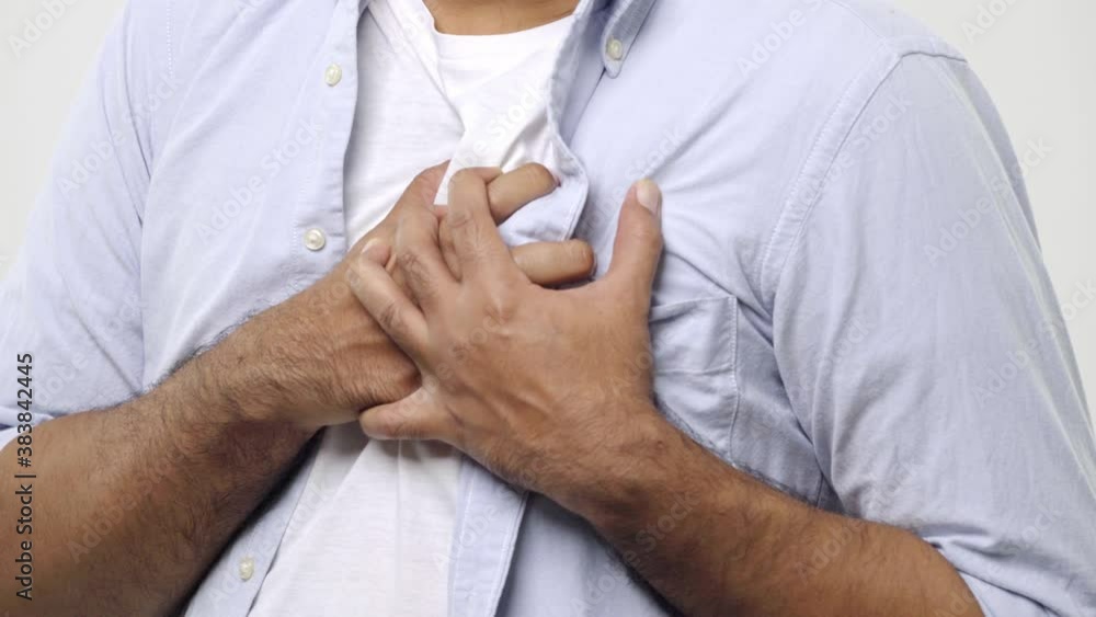 Close up. Man holding his chest with both hands, having heart attack or painful cramps, pressing on chest with painful expression isolated on white background. 4K Resolution. Close up. Man holding his chest with both hands, having heart attack or painful cramps, pressing on chest with painful expression isolated on white background. 4K Resolution.