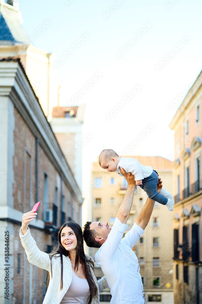 Happy young family taking a selfie with the phone in the street