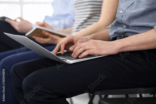 Group of casual dressed business people working at meeting or conference, close-up of hands. Businessman using laptop computer. Teamwork or coaching concept