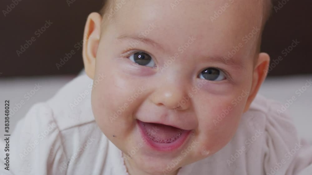 Beautiful Smiling Baby: A gorgeous little baby lies on the bed and smiles at the camera with a nice soft focus background. Beautiful Smiling Baby: A gorgeous little baby lies on the bed and smiles at the camera with a nice soft focus background.